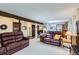 Spacious living room with carpeted floors, beamed ceilings, and two oversized burgundy sofas at 8155 Everett E St, Arvada, CO 80005