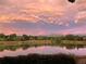 Scenic pond reflecting a colorful sunset with trees and mountains in the distance at 8155 Everett E St, Arvada, CO 80005