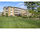 Low-rise condominium with manicured green lawn, lush shrubs, and mature trees at 610 S Alton Way # 7C, Denver, CO 80247