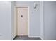 Apartment hallway leading to a door with modern light fixture and neutral decor at 610 S Alton Way # 7C, Denver, CO 80247