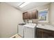 Functional laundry room featuring washer, dryer, cabinets, utility sink, and a bright window for natural light at 2633 Garganey Dr, Castle Rock, CO 80104