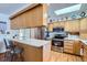 Well-lit kitchen featuring wooden cabinetry, stainless steel appliances, a breakfast bar, and a skylight at 1901 Blue Mountain Ave, Berthoud, CO 80513