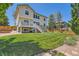 Expansive backyard with lush green lawn, deck, and mature trees for privacy at 13962 Dexter Way, Thornton, CO 80602