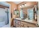 Well-lit bathroom featuring dual sinks, wooden cabinetry, and a shower-tub combo at 13962 Dexter Way, Thornton, CO 80602