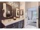 Modern bathroom featuring double vanity sinks, stylish framed mirrors, and an open doorway to the bedroom at 8445 S Holland Way # 205, Littleton, CO 80128