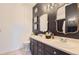 Modern bathroom with dual sinks, dark cabinets, neutral tile flooring, and decorative mirrors and lighting at 8445 S Holland Way # 205, Littleton, CO 80128