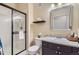 Bright bathroom featuring a glass-enclosed shower, toilet, and a single sink vanity with dark cabinets at 8445 S Holland Way # 205, Littleton, CO 80128