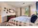 Well-lit bedroom with a queen bed with stylish gray and white bedding, lots of sunlight, and a wooden dresser at 8445 S Holland Way # 205, Littleton, CO 80128