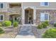 Close up of the exterior building entrance featuring stone accents, well-maintained landscaping and access to the units at 8445 S Holland Way # 205, Littleton, CO 80128