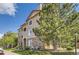 Inviting multi-story condo building featuring a mix of stone and vinyl siding, mature trees and manicured lawn at 8445 S Holland Way # 205, Littleton, CO 80128