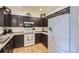 Modern kitchen with dark cabinetry, white appliances, and a spacious layout with wood flooring at 8445 S Holland Way # 205, Littleton, CO 80128