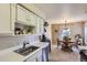 Efficient kitchen features white cabinetry and countertops with a stainless-steel sink and adjacent dining area at 7665 E Eastman Ave # 210, Denver, CO 80231