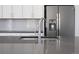 Close view of kitchen island sink with modern faucet, gray countertop, and stainless steel refrigerator at 3654 Penang Dr, Castle Rock, CO 80109
