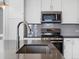 Close-up of sink and counter featuring stainless appliances, tile backsplash, and modern fixtures at 3654 Penang Dr, Castle Rock, CO 80109