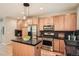 Kitchen with stainless appliances, wood cabinets, center island with black countertops, and modern lighting at 453 S Quay Street, Lakewood, CO 80226