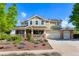 Inviting two-story home featuring a charming front porch, lush landscaping, and solar panels on the roof at 21395 E Greenwood Pl, Aurora, CO 80013