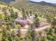 Aerial view of a brick home with garages surrounded by trees and winding roads in a mountain setting at 6094 Pyrenees Trl, Golden, CO 80403