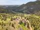 Expansive aerial view of a property with multiple structures surrounded by lush forests and rolling hills at 6094 Pyrenees Trl, Golden, CO 80403
