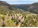 Gorgeous aerial view of a home nestled in a lush valley with towering trees and rolling hills at 6094 Pyrenees Trl, Golden, CO 80403