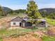 A mountain home and metal outbuilding with a fenced in yard at 6094 Pyrenees Trl, Golden, CO 80403