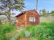 Exterior view of a wooden shed featuring a window, small access door and natural surroundings at 6094 Pyrenees Trl, Golden, CO 80403