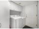 Bright laundry room features a full-sized washer and dryer and ample upper cabinet storage for supplies at 7696 S Hudson Way, Centennial, CO 80122