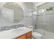 This bathroom offers a round mirror, modern vanity lighting, and shower with tiled surround and glass door at 1371 W 133Rd Way, Denver, CO 80234