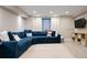 Spacious basement with a large blue sectional sofa, area rug and entertainment area at 3103 S Cherokee St, Englewood, CO 80110