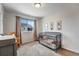 Bedroom features a metal crib, plush carpet, and natural light from the bright window at 17851 E 103Rd Ave, Commerce City, CO 80022