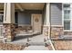 Inviting front porch with stone pillars, decorative wreath on the door, and charming lantern accents at 17851 E 103Rd Ave, Commerce City, CO 80022