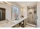 Bright bathroom featuring a dual sink vanity with wood cabinets, quartz countertop, and walk-in shower at 2323 S High St, Denver, CO 80210