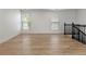 Bonus room with wood-look floors, two windows, and dark-stained banister and railing at 18396 E Mexico Pl, Aurora, CO 80017