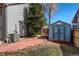 Fenced in backyard with a well-maintained lawn, garden shed, stone path, and mature trees at 6527 Torrey Ct, Arvada, CO 80007