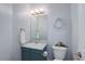 Charming powder room with a decorative wreath, blue vanity, and a round mirror at 6527 Torrey Ct, Arvada, CO 80007