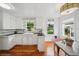 Bright kitchen featuring white cabinets, hardwood floors, and a window overlooking the backyard at 113 S 4Th Ave, Brighton, CO 80601