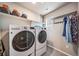 Functional laundry room with modern washer and dryer, storage shelves, and clothing rack at 18103 House Finch Ln, Parker, CO 80134