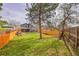 Spacious backyard with a manicured lawn, wooden fence, mature trees, and a covered patio at 10866 W Half Moon Pass, Littleton, CO 80127