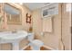Small bathroom with pedestal sink, toilet, window, and a framed mirror at 10866 W Half Moon Pass, Littleton, CO 80127