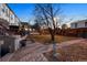 Paver patio leads to a spacious backyard with lush grass, mature trees, and surrounding properties at 1581 N Ogden St, Denver, CO 80218