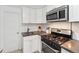Kitchen featuring white cabinets, stainless steel appliances, and dark countertop at 1581 N Ogden St, Denver, CO 80218