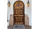 An ornate wooden door has carved details and decorative sconces on either side at 34498 Forest Estates Rd, Evergreen, CO 80439