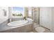 Bathroom featuring a soaking tub with a view and separate glass enclosed shower at 985 Penstemon Dr, Henderson, CO 80640