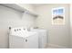A bright laundry room with a window, a shelf, and side-by-side white washer and dryer at 985 Penstemon Dr, Henderson, CO 80640
