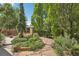 Landscaped backyard featuring a shed, stone pathway, and a variety of mature trees and plantings, offering a private outdoor retreat at 7513 Simms Ct, Arvada, CO 80005