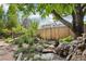A serene backyard with a stone pathway and a small water feature nestled among lush greenery and a wooden fence at 7513 Simms Ct, Arvada, CO 80005