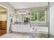 Bright bathroom featuring double sinks, a soaking tub, and a window providing natural light at 7513 Simms Ct, Arvada, CO 80005