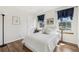 Well-lit bedroom featuring hardwood floors, a queen bed, two windows, and blue decorative curtains at 7513 Simms Ct, Arvada, CO 80005