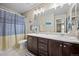 Bright bathroom with a double sink vanity, white countertop, and a blue-striped shower curtain at 7967 E 139Th Pl, Thornton, CO 80602
