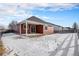 Backyard of home with covered patio, snow-covered grass, and wooden fence at 6321 Spring Gulch St, Frederick, CO 80516