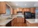 Kitchen with wood cabinets, black appliances, and an island at 6321 Spring Gulch St, Frederick, CO 80516